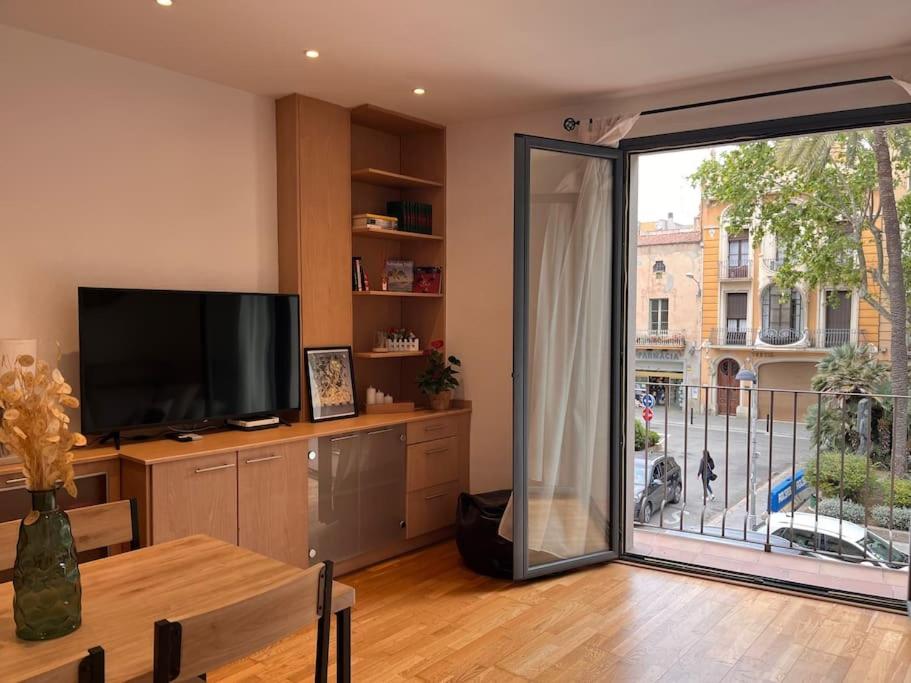 sala de estar con una gran puerta corredera de cristal que da a un balcón en Piso céntrico y acogedor, en Figueres