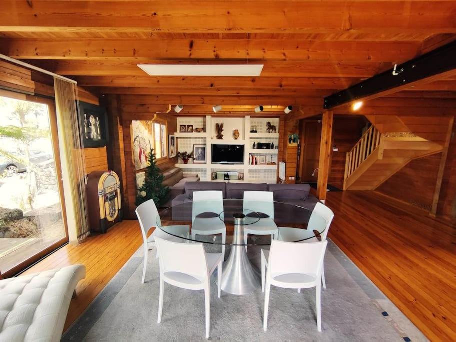 a dining room with a glass table and white chairs at Le Chalet des Cévennes in La Plaine des Cafres