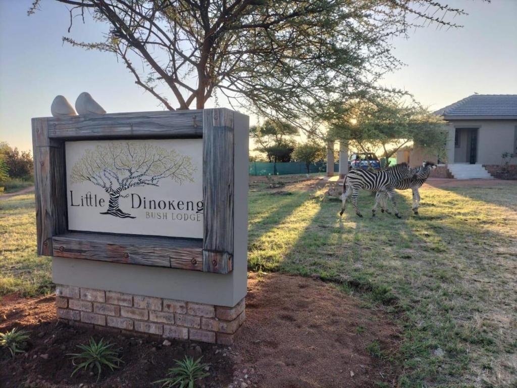 a zebra standing next to a sign in a field at Little Dinokeng Bush Lodge in Klipdrift