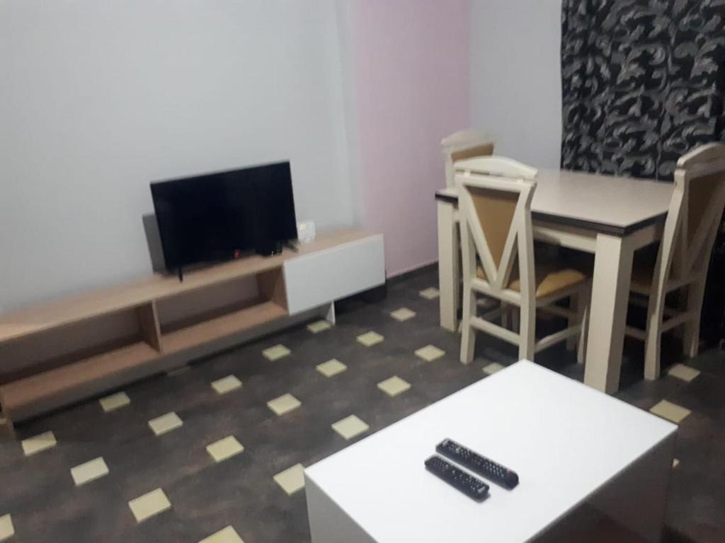 een woonkamer met een tv en een tafel en stoelen bij Apartament in Shëngjin
