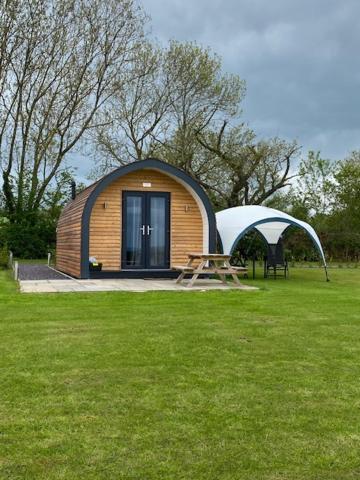 a small hut with a picnic table in a field at Honeypot Hideaways Luxury Glamping - Exclusively for Adults in Chester