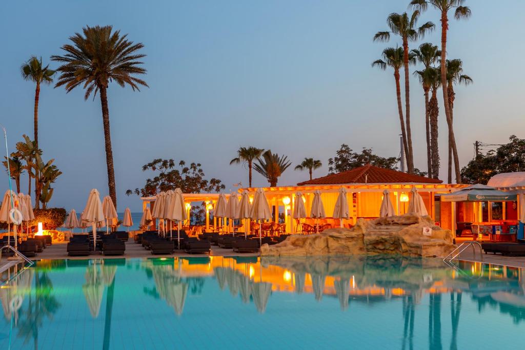 a swimming pool with umbrellas and a resort at Pavlo Napa Beach Hotel in Ayia Napa