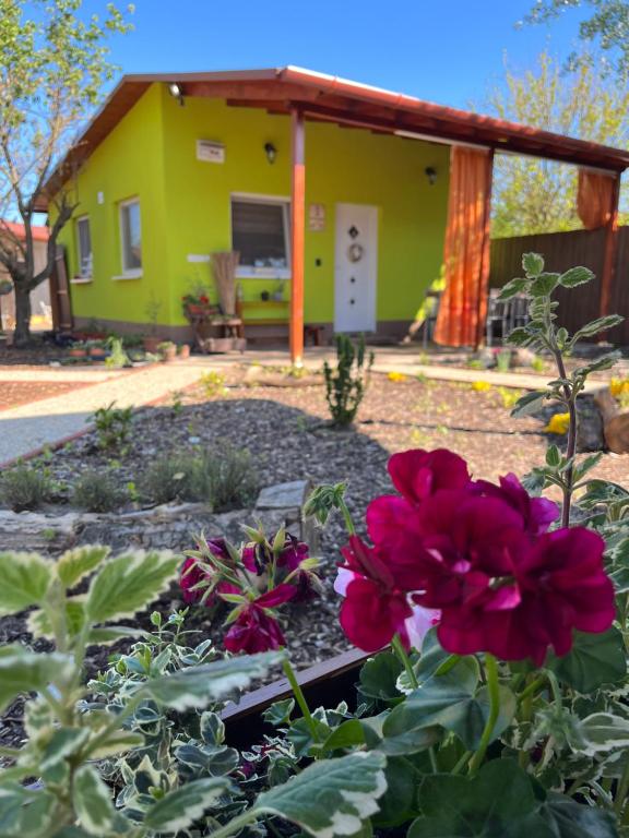 una casa con un jardín con flores delante en Arvisura Vendégházak family friendly transit apartments en Zsombó