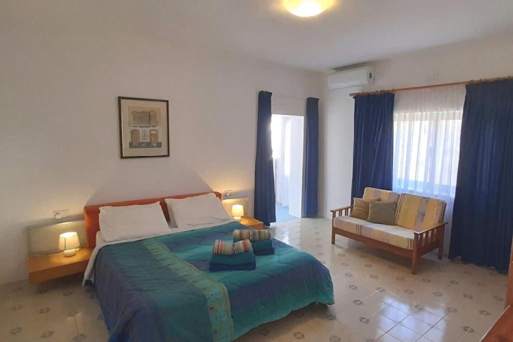 een grote slaapkamer met een groot bed en een stoel bij Villa Bronja Superior Airconditioned Studio apartment in Xlendi in Xlendi