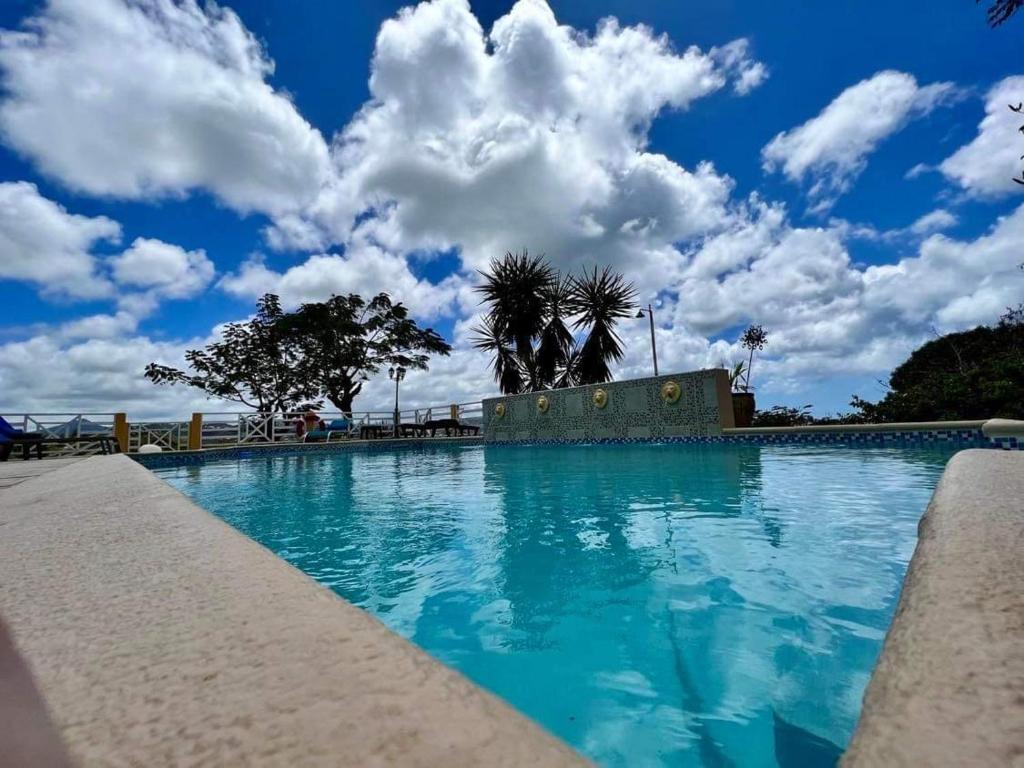 a large swimming pool with a blue sky with clouds at Kay Nou Apartments in Gros Islet