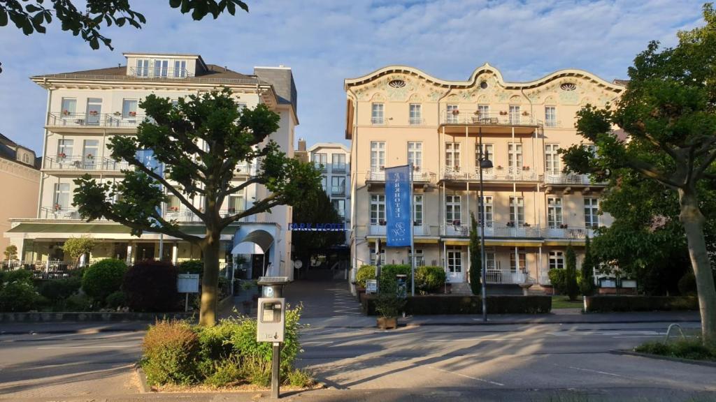 uma rua com dois grandes edifícios e uma árvore em Parkhotel Bad Homburg em Bad Homburg vor der Höhe