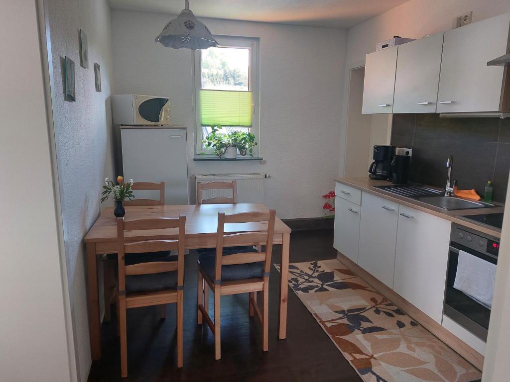 a small kitchen with a wooden table and chairs at Pension am Sonnenhof in Schmalkalden