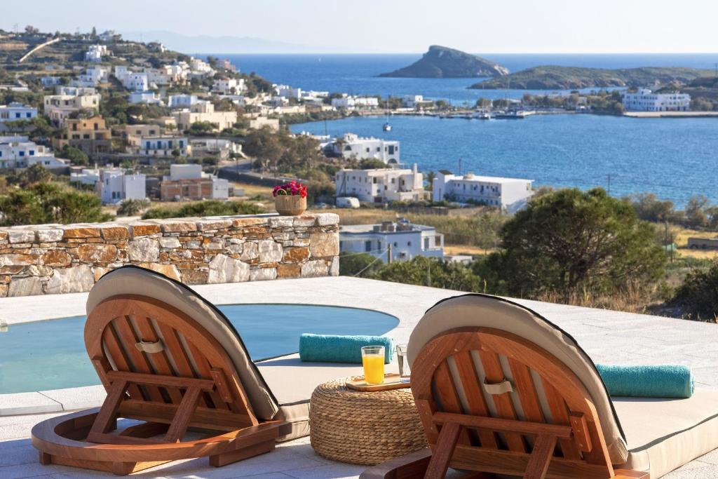 a couple of chairs sitting next to a swimming pool at Syros Grace eco-Villa with Jacuzzi & Stuning Views in Ano Syros