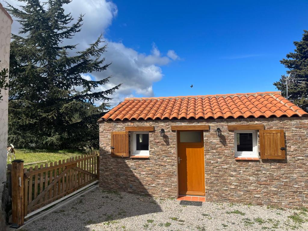 ein kleines Backsteinhaus mit einem Holzzaun in der Unterkunft GITE DE L'AUXINEILL in Castelnou