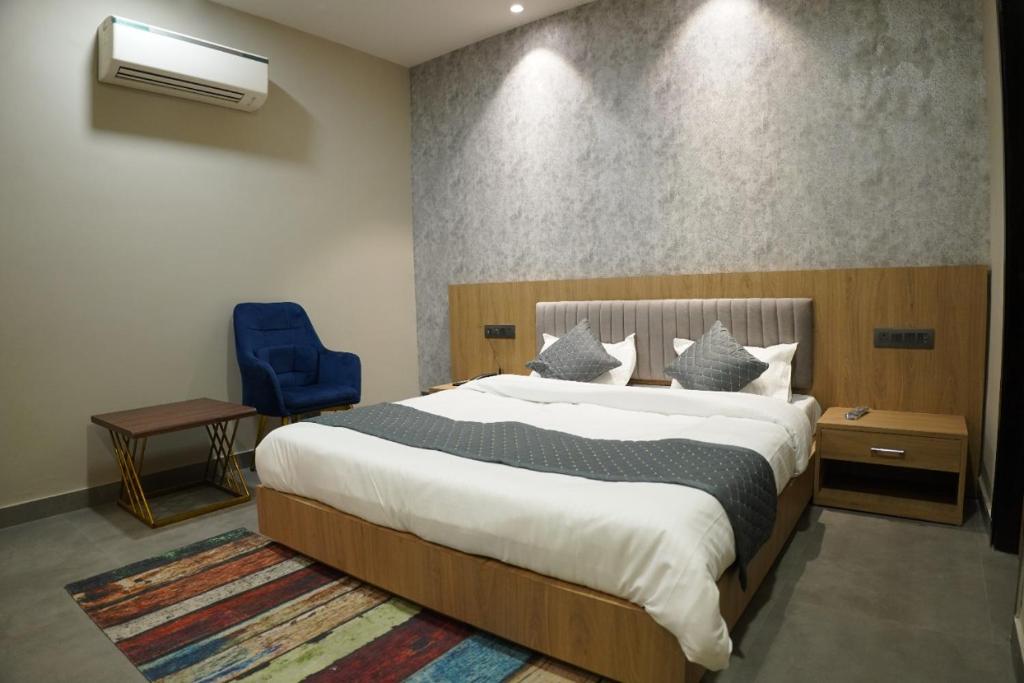 a bedroom with a large bed and a blue chair at HOTEL CENTRAL PARK in Bathinda