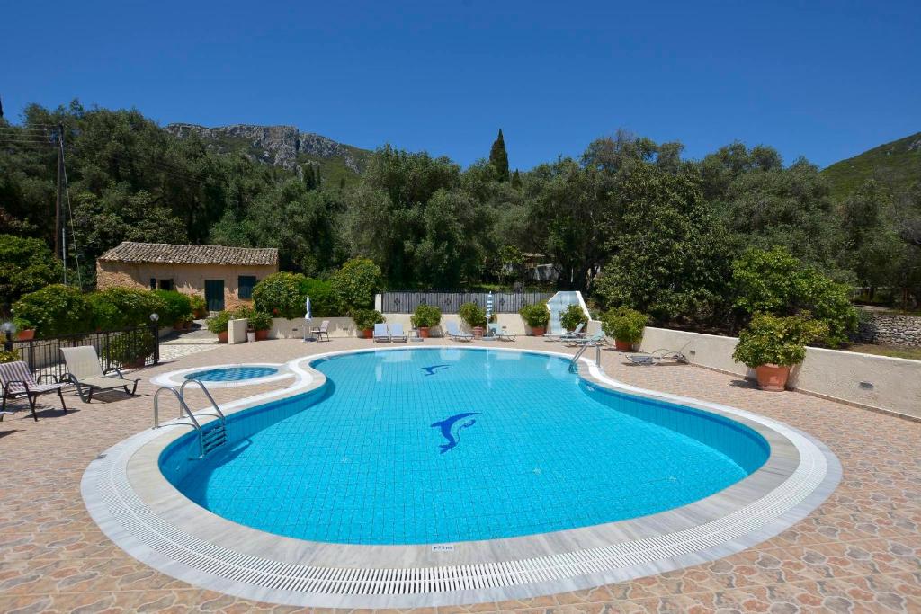 uma grande piscina num pátio com cadeiras e uma casa em Marilena Studios And Apartments em Paleokastritsa