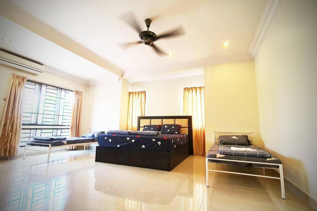 a room with three beds and a ceiling fan at Puchong Semi D Homestay spacious 4 rooms in Puchong