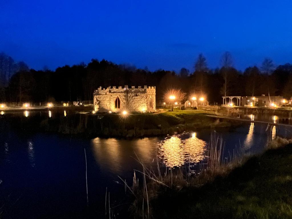 an old castle sitting on the side of a lake at night at Ironland Roztocze 