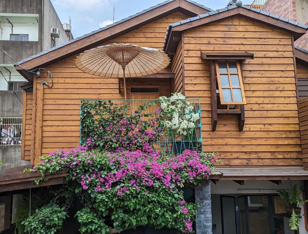 ein Holzhaus mit Blumen und einem Regenschirm in der Unterkunft Spring12 House in Chiayi