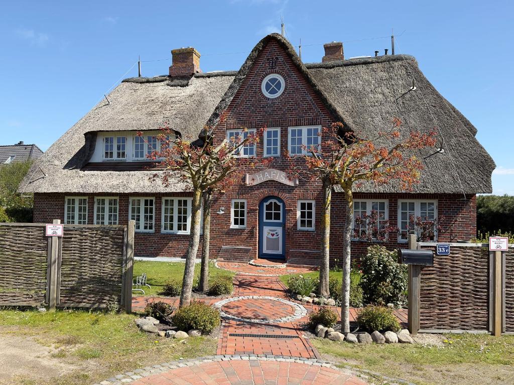 a large brick house with a thatched roof at Friesenhof, Haus Hafis, Whg 9 in Nebel