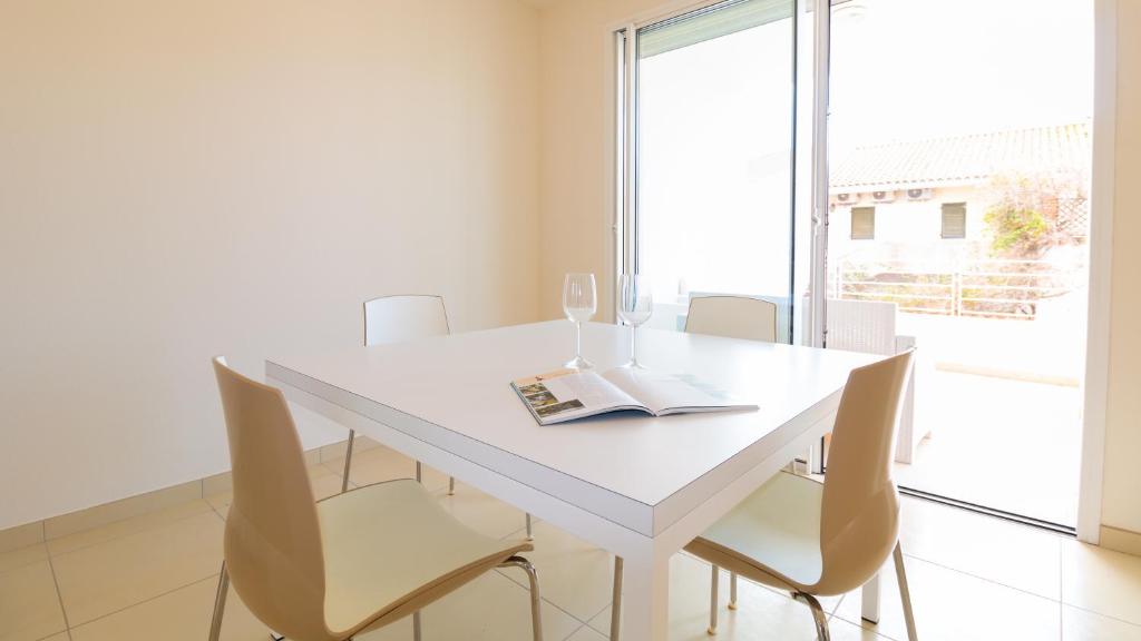 un comedor blanco con una mesa y sillas blancas en Welcomely - Civico 48, en Torre Grande