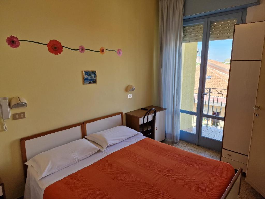 um quarto com uma cama e uma janela com flores na parede em HOTEL CLARA RIMINI 30m from the beach em Rimini