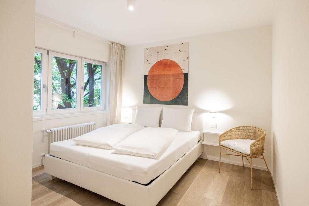 una camera bianca con un letto e una sedia di Italyescapes Delia a Merano