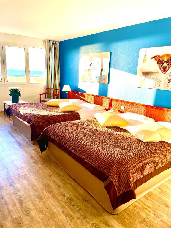 two beds in a room with blue walls at Hotel de l&#39;Europe in Dieppe