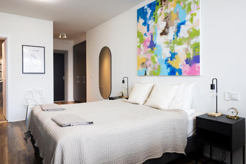 a bedroom with a white bed and a painting on the wall at Modern Downtown 1 BR Apartment in Reykjavík