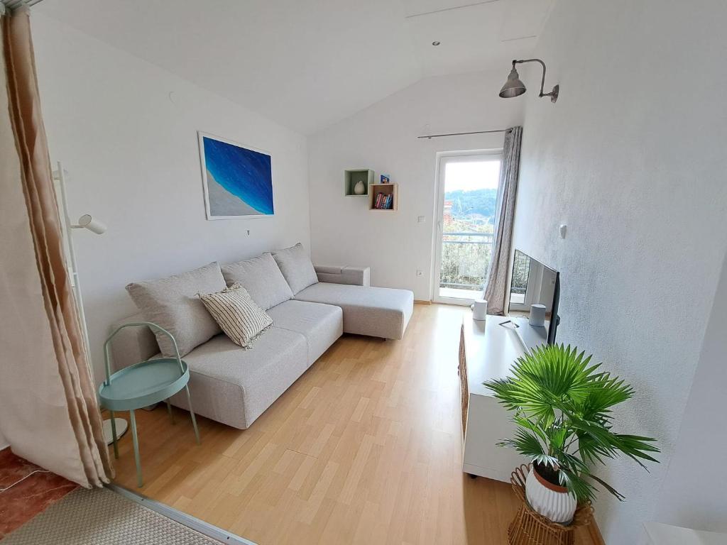 a white living room with a couch and a plant at Villa Porto in Rogač