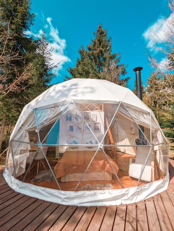 une tente igloo sur une terrasse en bois dans l'établissement Medve Dome - Luxury Camping in the middle of nature, à Vlăhiţa