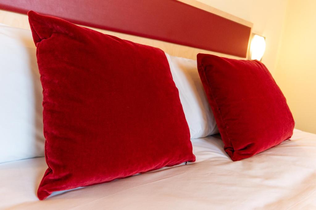 two red pillows sitting on top of a bed at Hotel Autoespresso Venice - Atika & Atif in Marghera