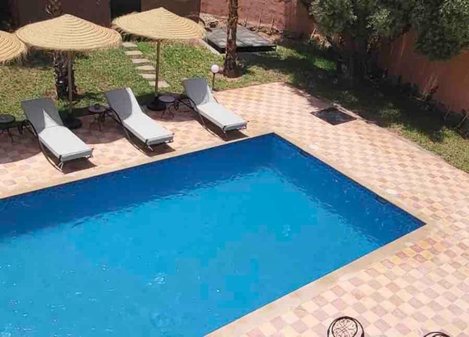 a blue swimming pool with chairs and umbrellas at Villa privative tortues2 piscine individual 35min in Marrakech