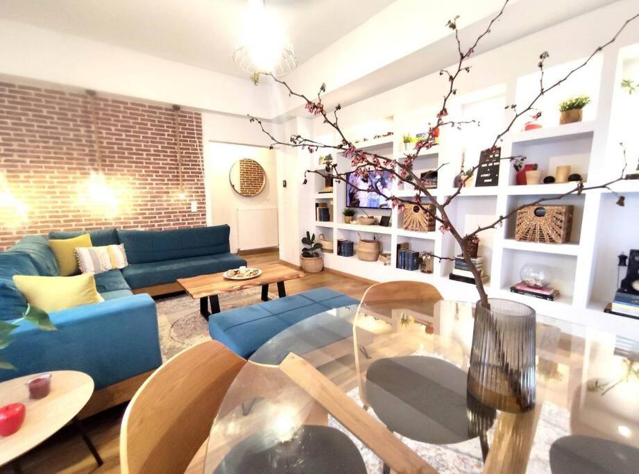 Voukamvilia Boutique Apartment في Ágios Matthaíos: غرفة معيشة مع أريكة زرقاء وطاولة زجاجية
