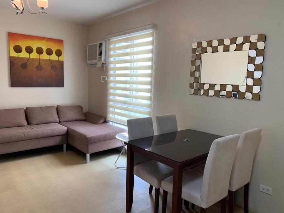 a living room with a table and a couch at Homey 2 BR Unit w/Pool in Avida IT Park in Cebu City