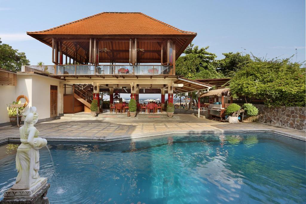 a swimming pool in front of a house with a building at Respati Beach Hotel in Sanur