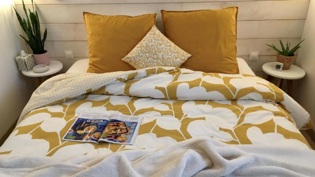 a bed with a blanket and a book on it at Maison d hôtes Casa Sana in Pillac