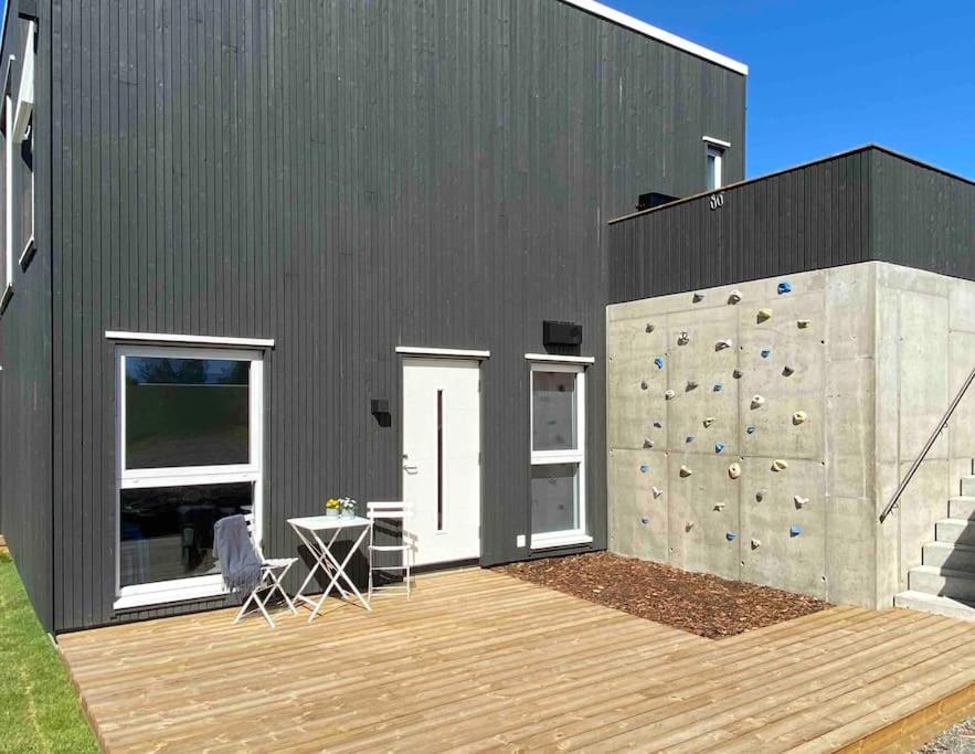 Apartment in Hafjell / Øyer centre. في هافيل: مبنى أسود مع جدار تسلق وسطح خشبي