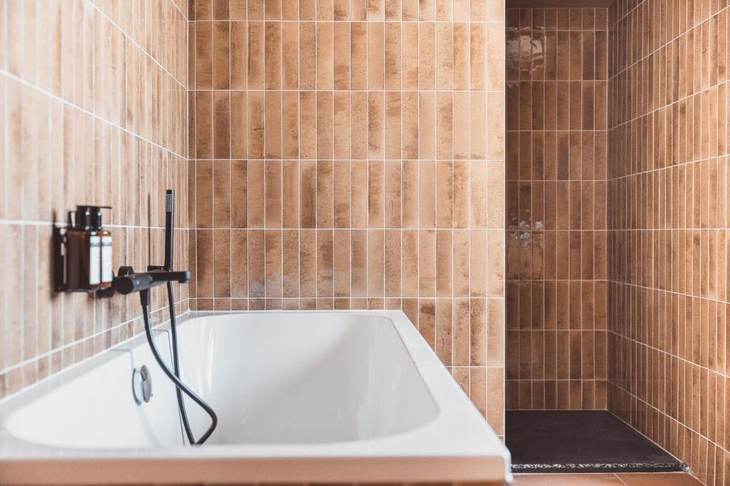 a bath tub in a bathroom with brown tiles at La Voie Lactée in La Mongie