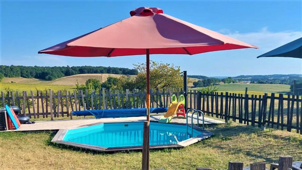 a red umbrella sitting next to a swimming pool at Maison d hôtes Casa Sana in Pillac