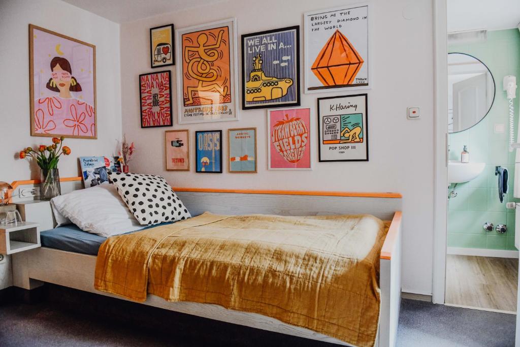 ein Schlafzimmer mit einem Bett mit einem Haufen Bilder an der Wand in der Unterkunft sleepArt room for 1 in Celle