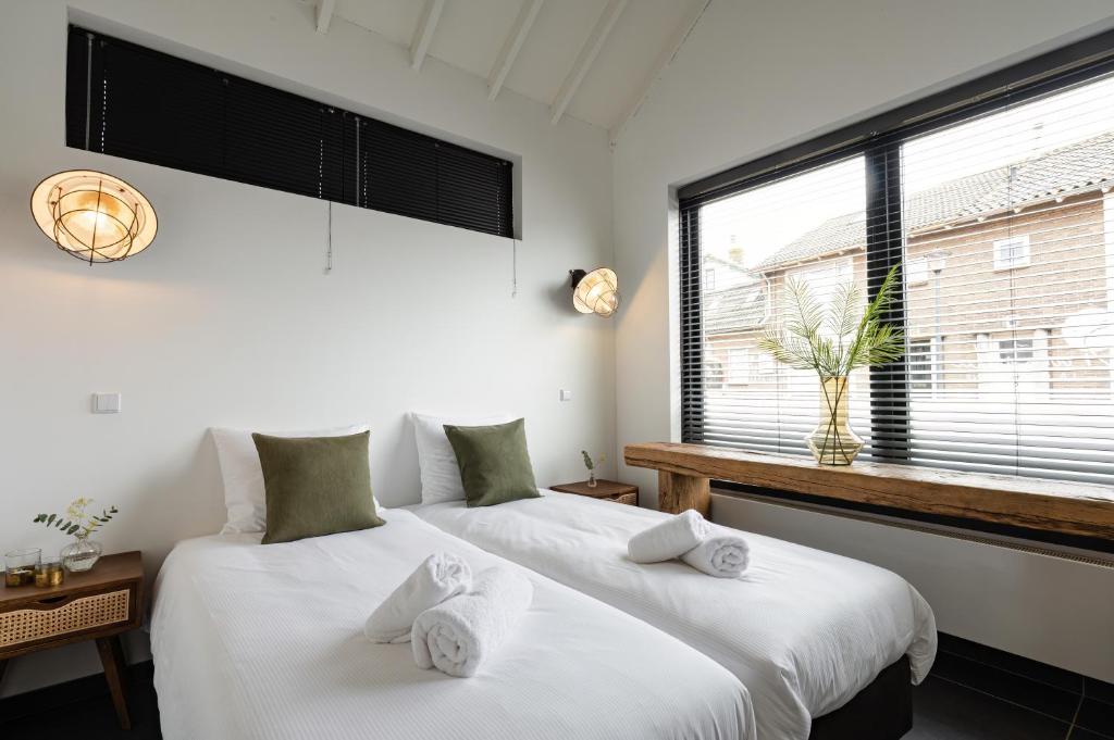 Dos camas en una habitación con dos ventanas. en Villa La Chatelaine, en Egmond aan Zee