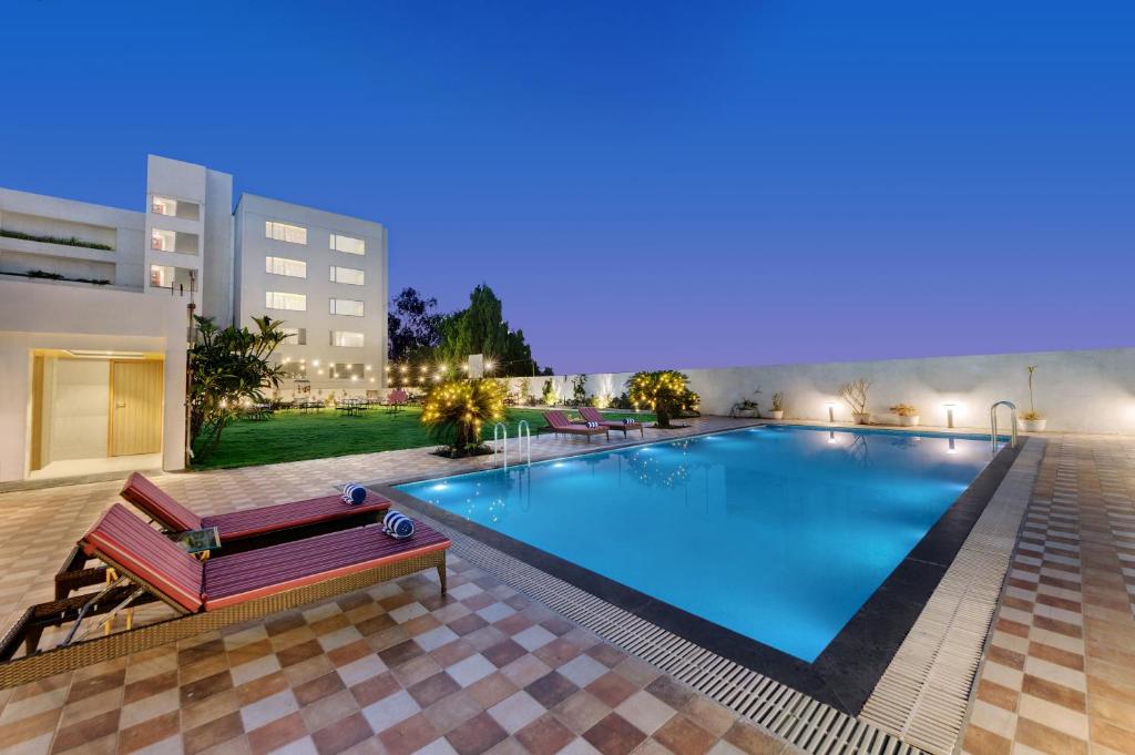 una gran piscina con un banco frente a un edificio en Amarpreet, Chhatrapati Sambhajinagar - AM Hotel Kollection, en Aurangabad