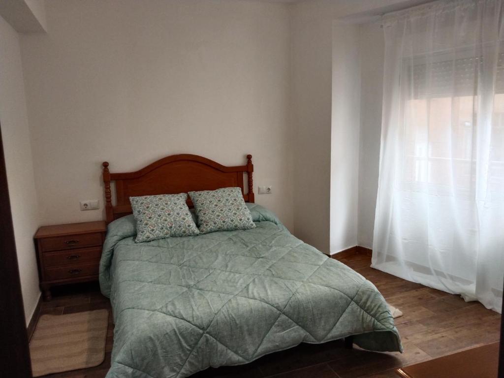 um quarto com uma cama com duas almofadas e uma janela em Apartamento Aitue em Gijón