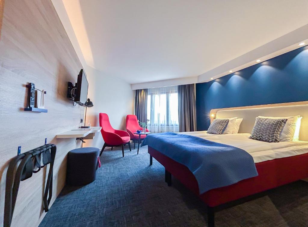 Habitación de hotel con cama y sillas rojas en Good Morning + Helsingborg, en Helsingborg