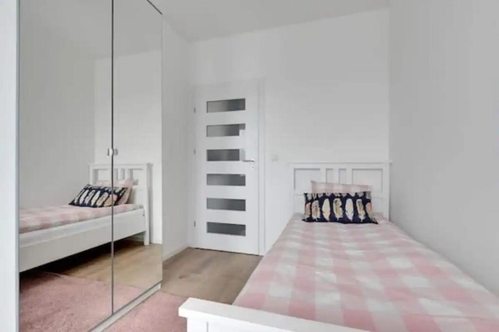 a white bedroom with two beds and a mirror at Golden Apartments&Glamping-DG10 in Gdańsk