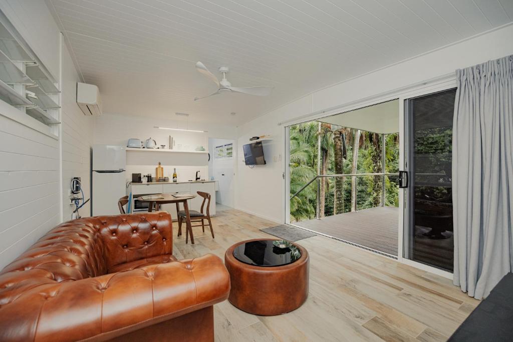 a living room with a leather couch and a table at mist at Cape Tribulation in Cape Tribulation