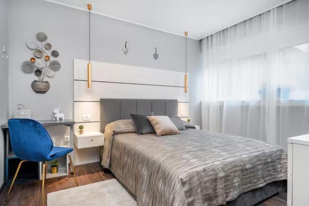 a bedroom with a bed and a blue chair at Apartman Megi in Šibenik