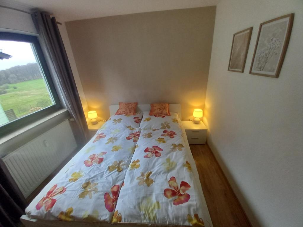 a bedroom with a bed with a floral bedspread and a window at Ferienwohnung Sophia in Nohfelden