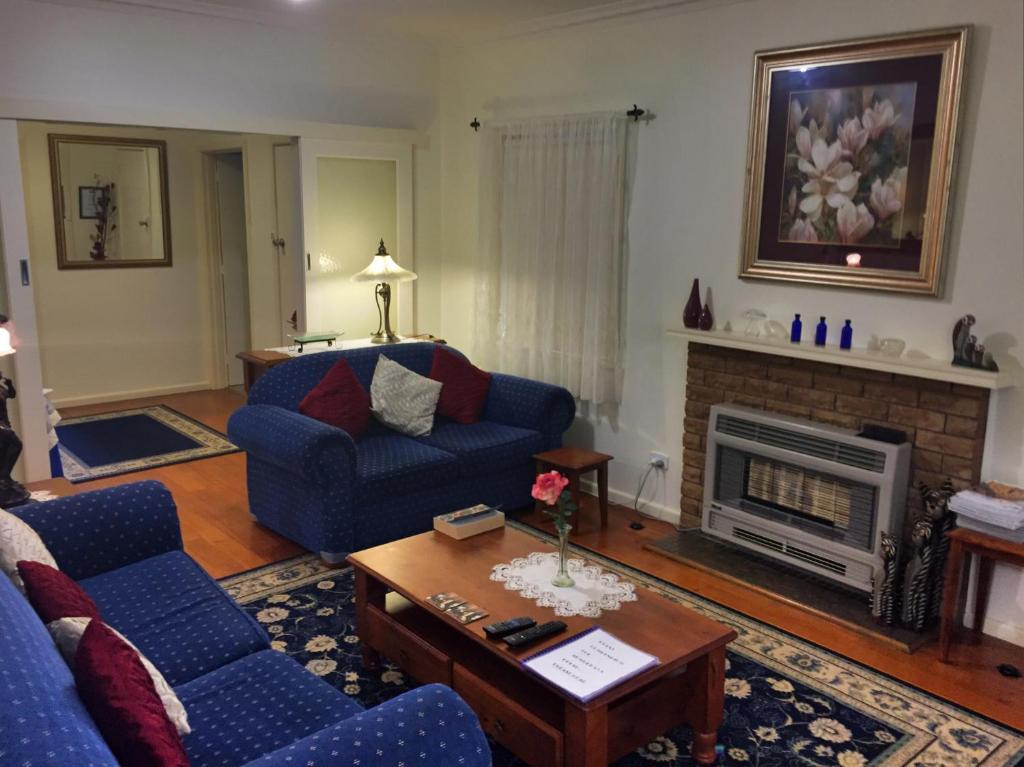 a living room with a blue couch and a fireplace at Admurraya House Bed & Breakfast in Rutherglen
