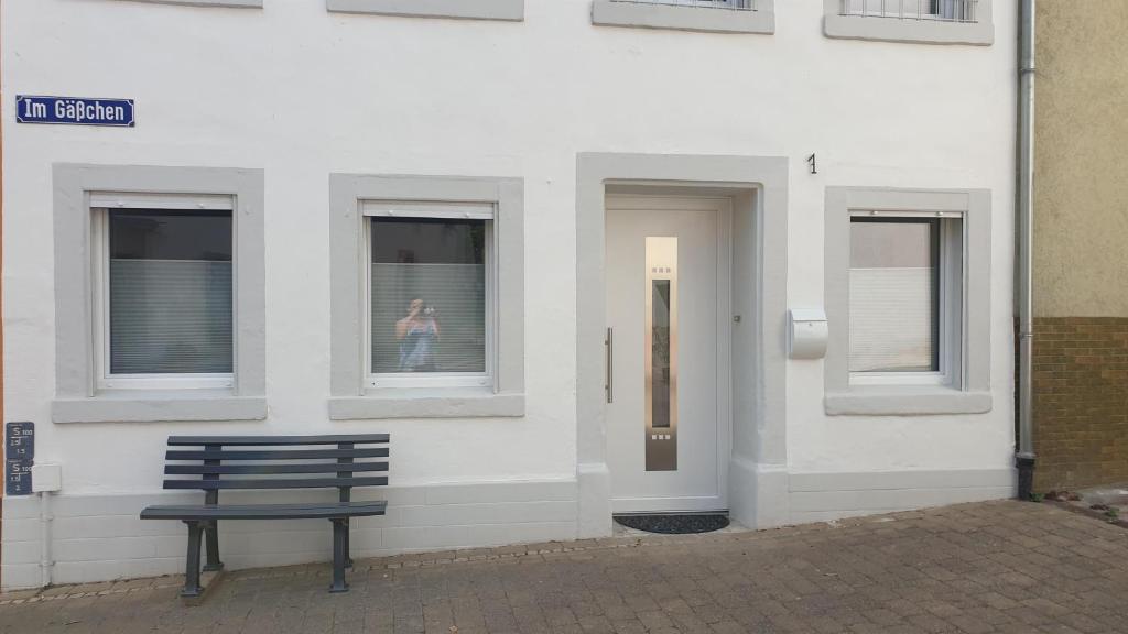 ławka siedząca przed budynkiem z osobą w oknie w obiekcie Ferienhaus Im Gäßchen w mieście Kordel