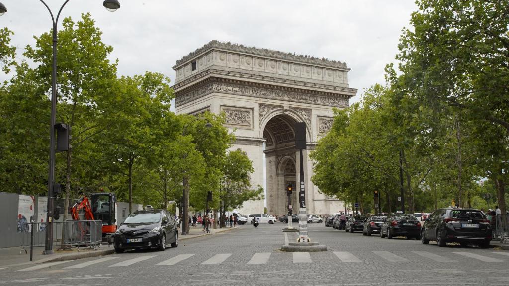 une arche dans une ville avec des voitures garées dans une rue dans l'établissement Hotel Phenix Paris, à Paris