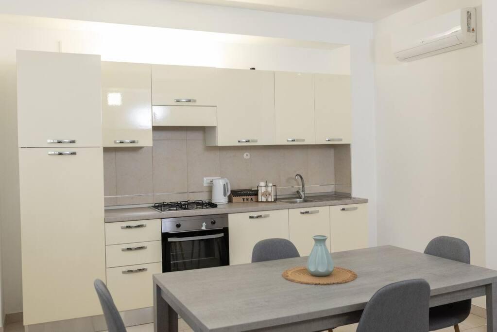 una cocina con armarios blancos y una mesa con sillas. en Casa Magenta Centro città, en Cerignola