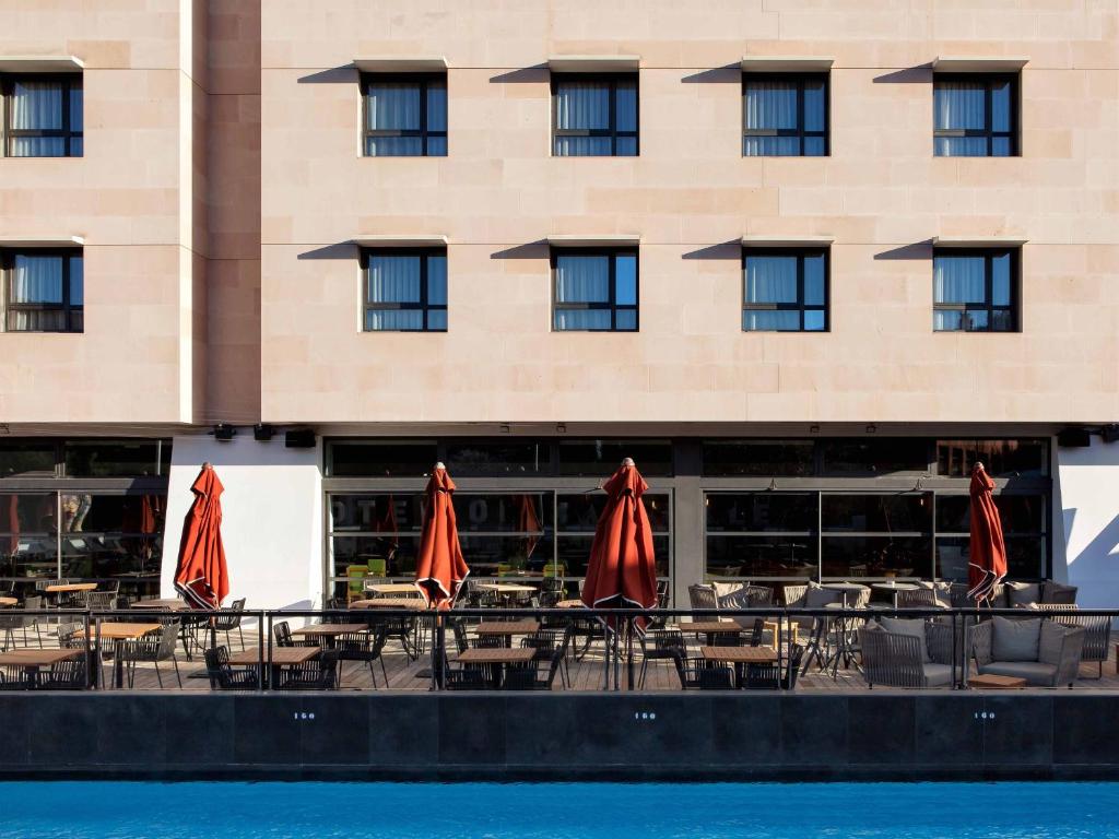 a hotel with tables and umbrellas in front of a building at New Hotel of Marseille - Vieux Port in Marseille
