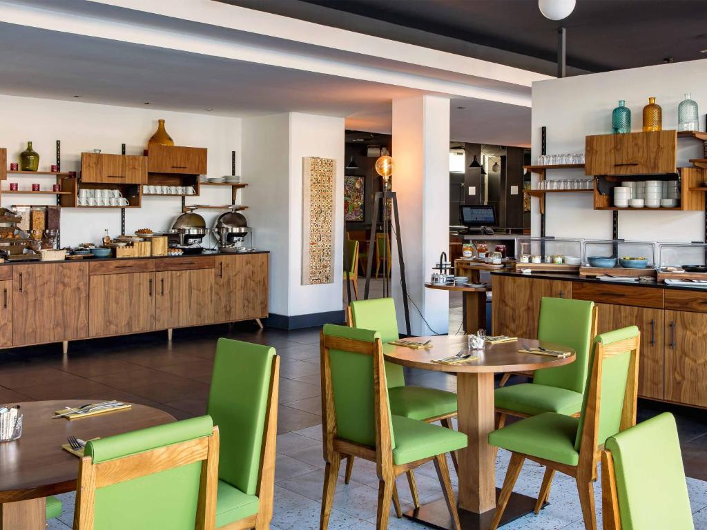 a restaurant with wooden tables and green chairs at New Hotel of Marseille - Vieux Port in Marseille